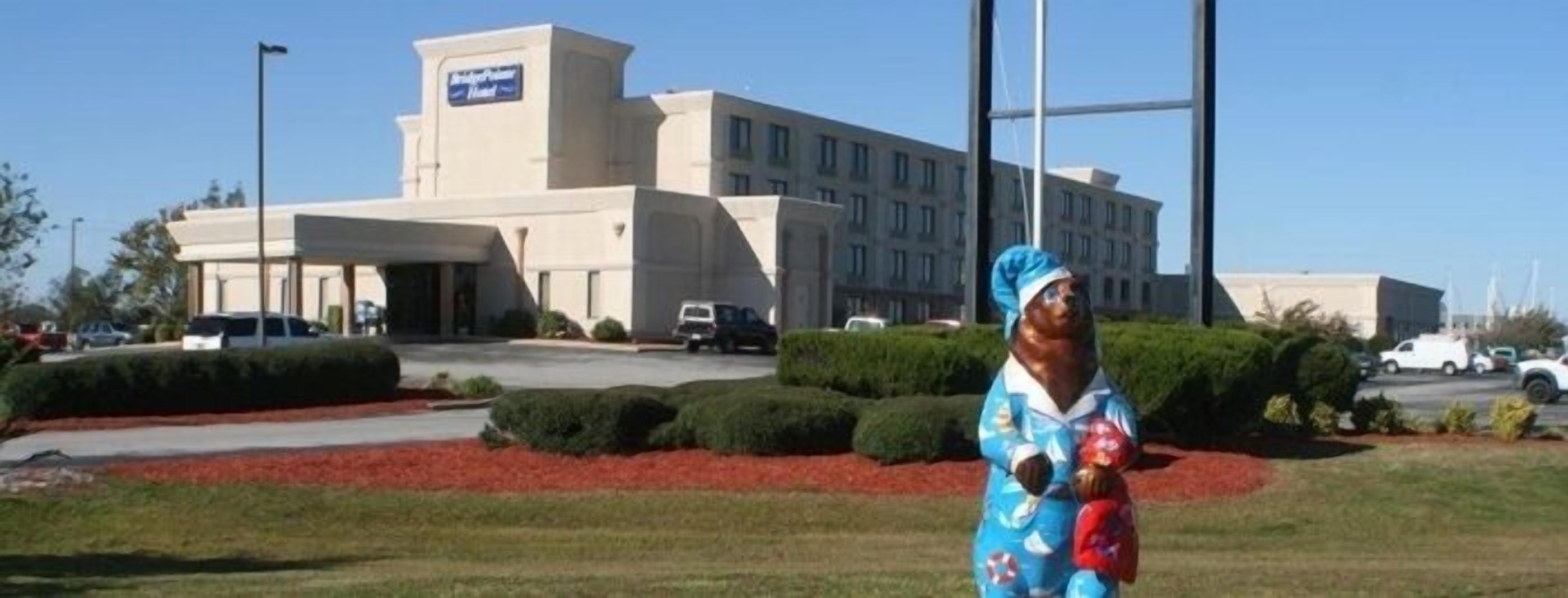 A hotel with a large building, a parking lot, and well-maintained landscaping.