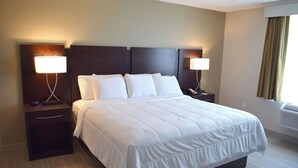 Una habitación de hotel con una cama grande, dos mesitas de noche y dos lámparas fijadas a la pared.