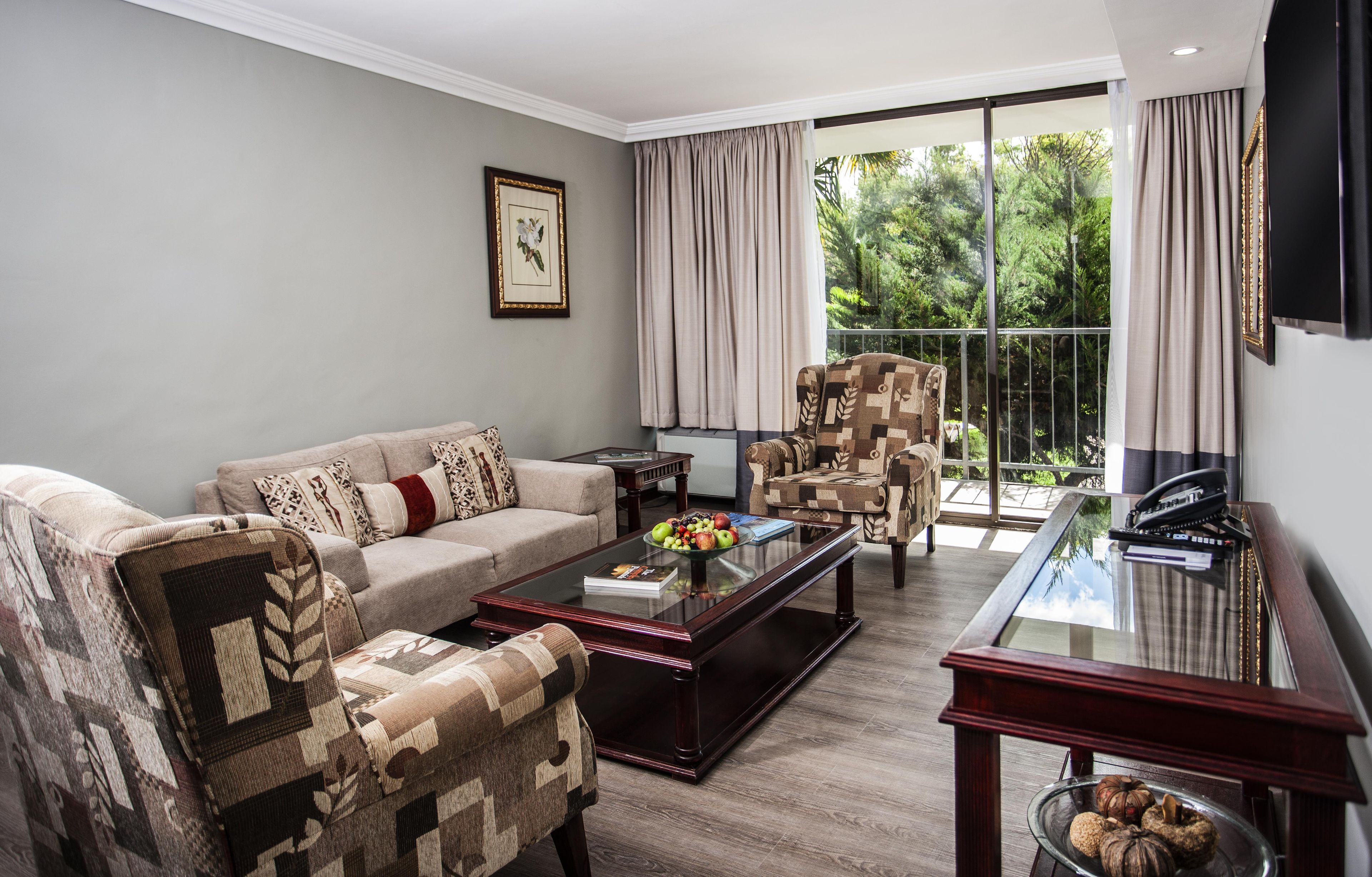 A living room with a sofa, armchairs, a coffee table, and a TV.
