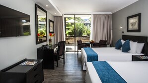 A hotel room with two beds, a desk, a chair, a TV, and a view of the garden. - Avani Maseru Hotel (Maseru)
