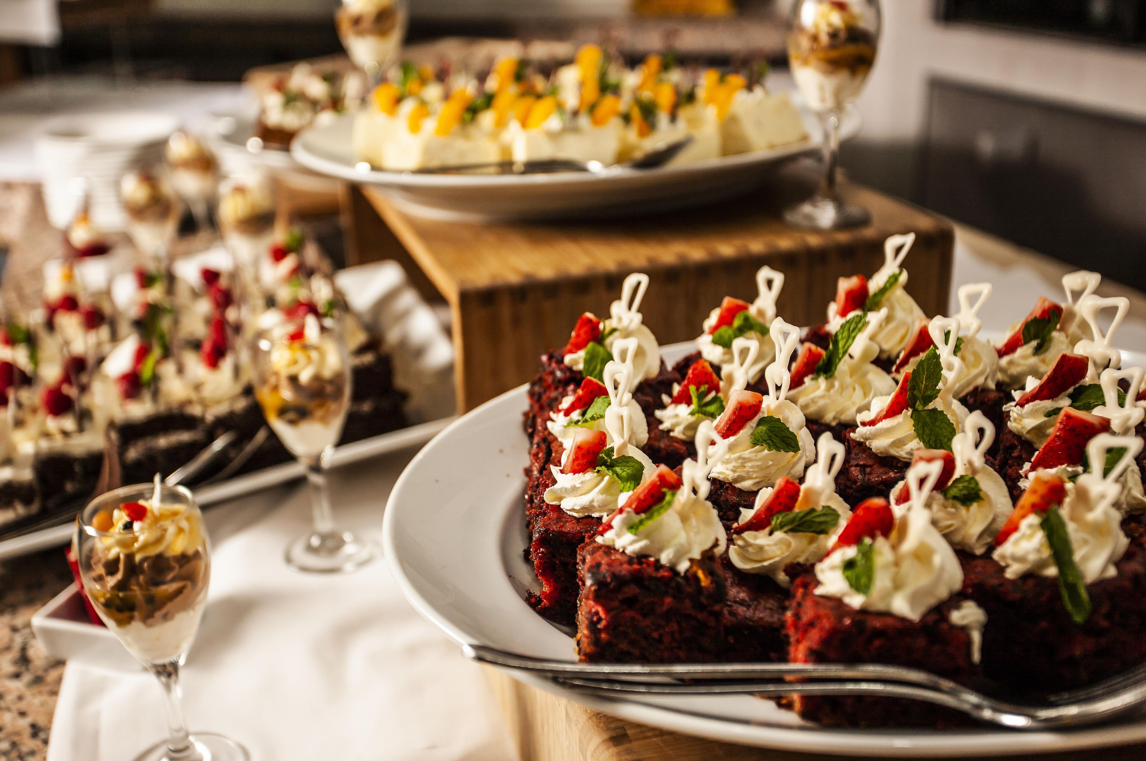 A dessert buffet with various plated desserts and a glass of dessert wine.