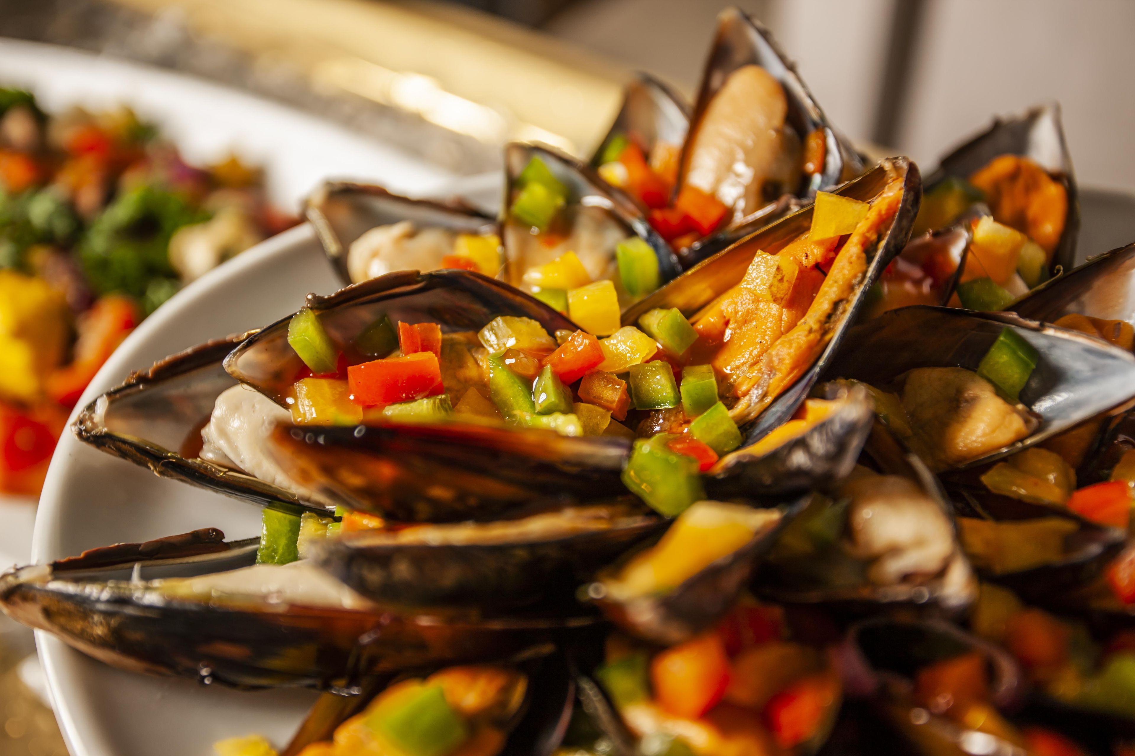 A plate of mussels with diced vegetables.