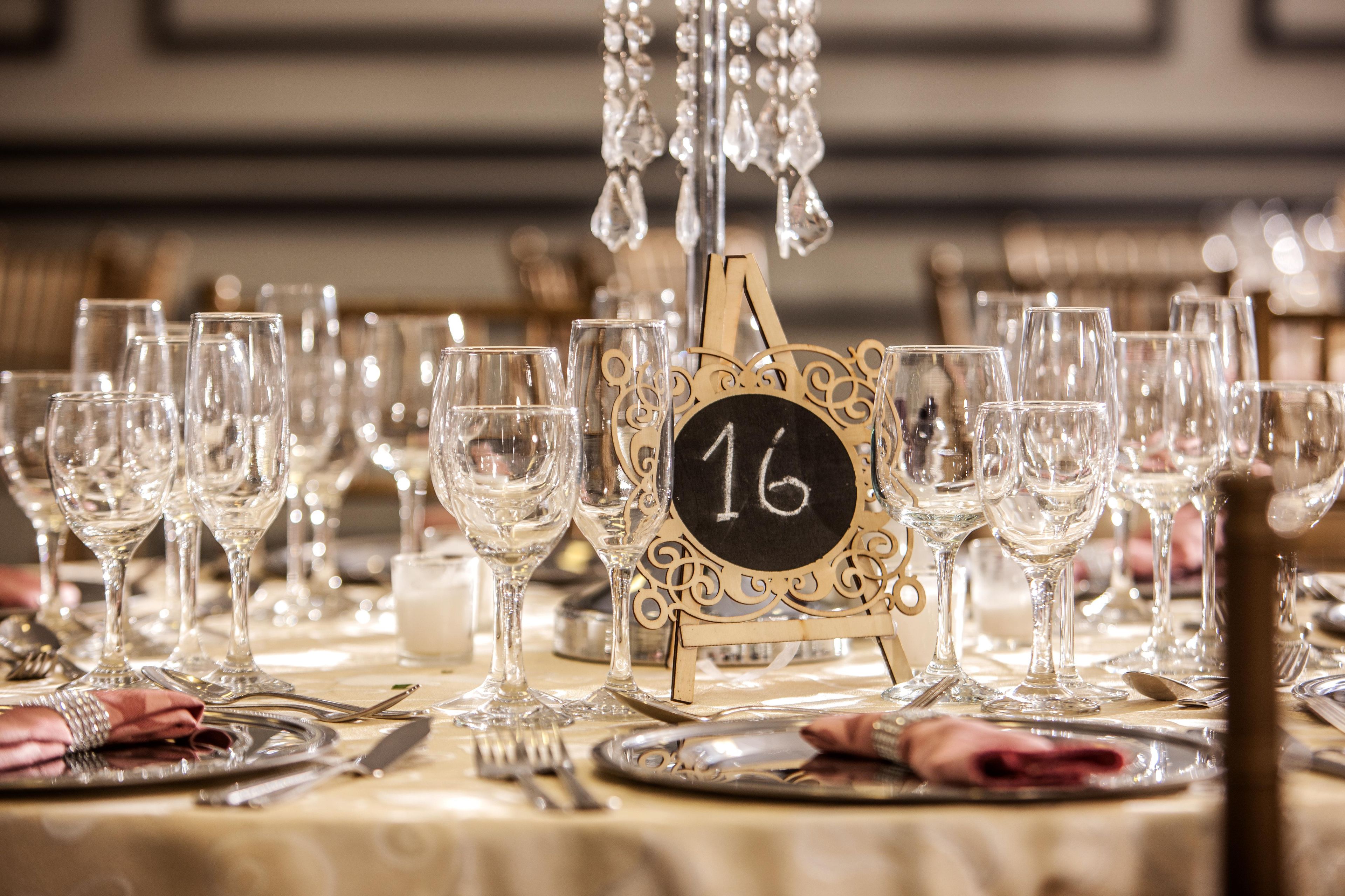 A table set with multiple wine glasses, a number sign, and cutlery.