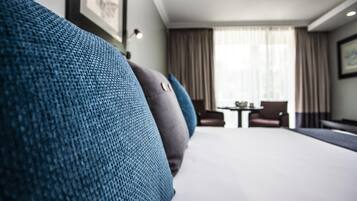 A hotel room with a large bed, a small table, and a chair.