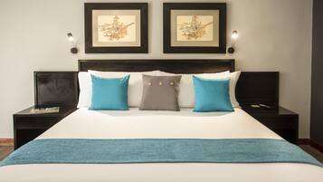 A hotel room with a large bed, two nightstands, a headboard, and two wall-mounted lamps.
