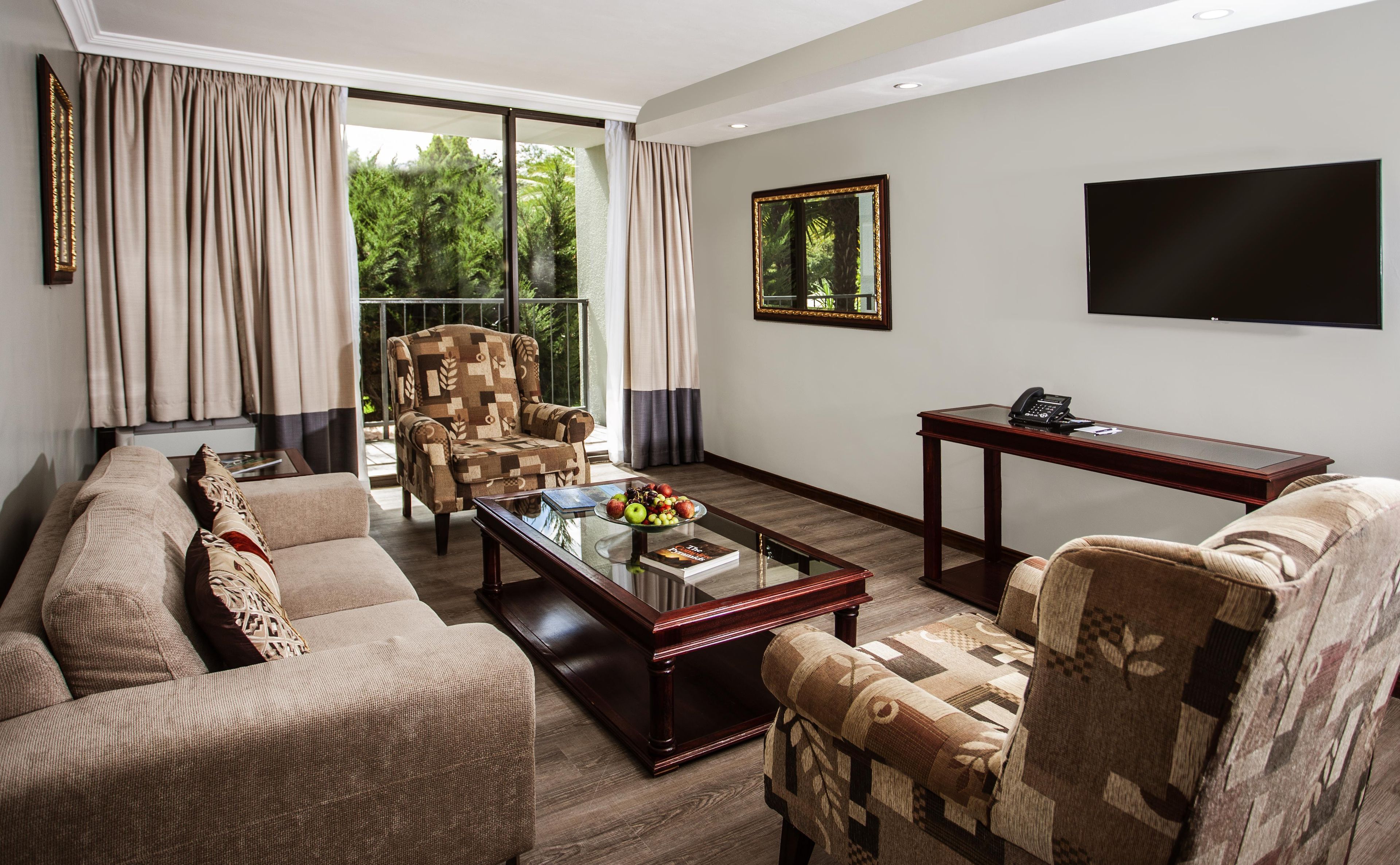 A living room with a sofa, armchair, coffee table, and a flat-screen TV.