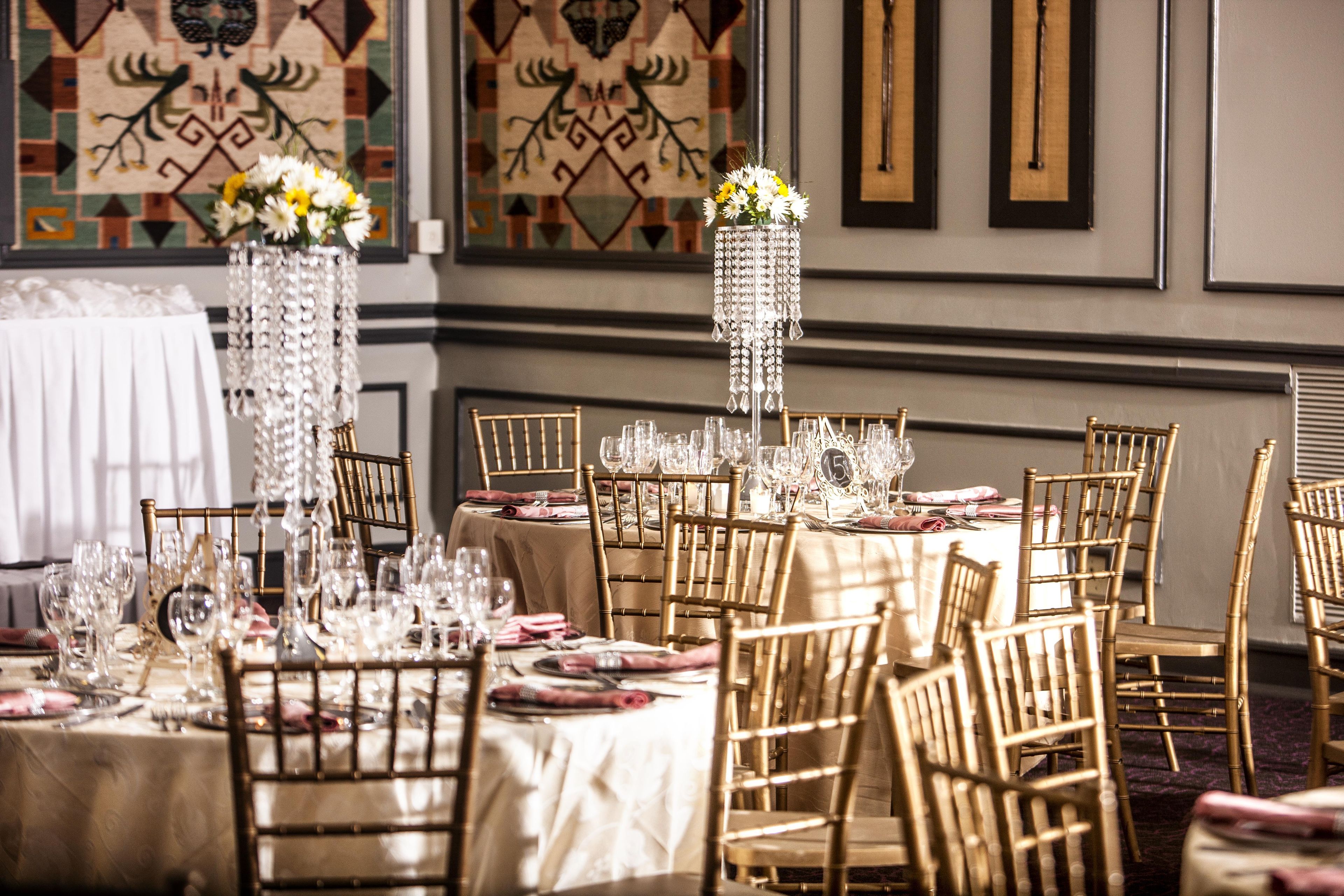 Un salón de banquetes con mesas redondas, sillas y una araña.