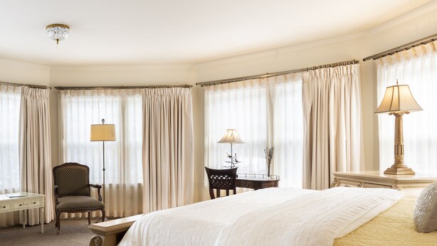 A hotel room with a large bed, a desk, a chair, and two lamps. - The Inn at Thorn Hill & Spa (Jackson)