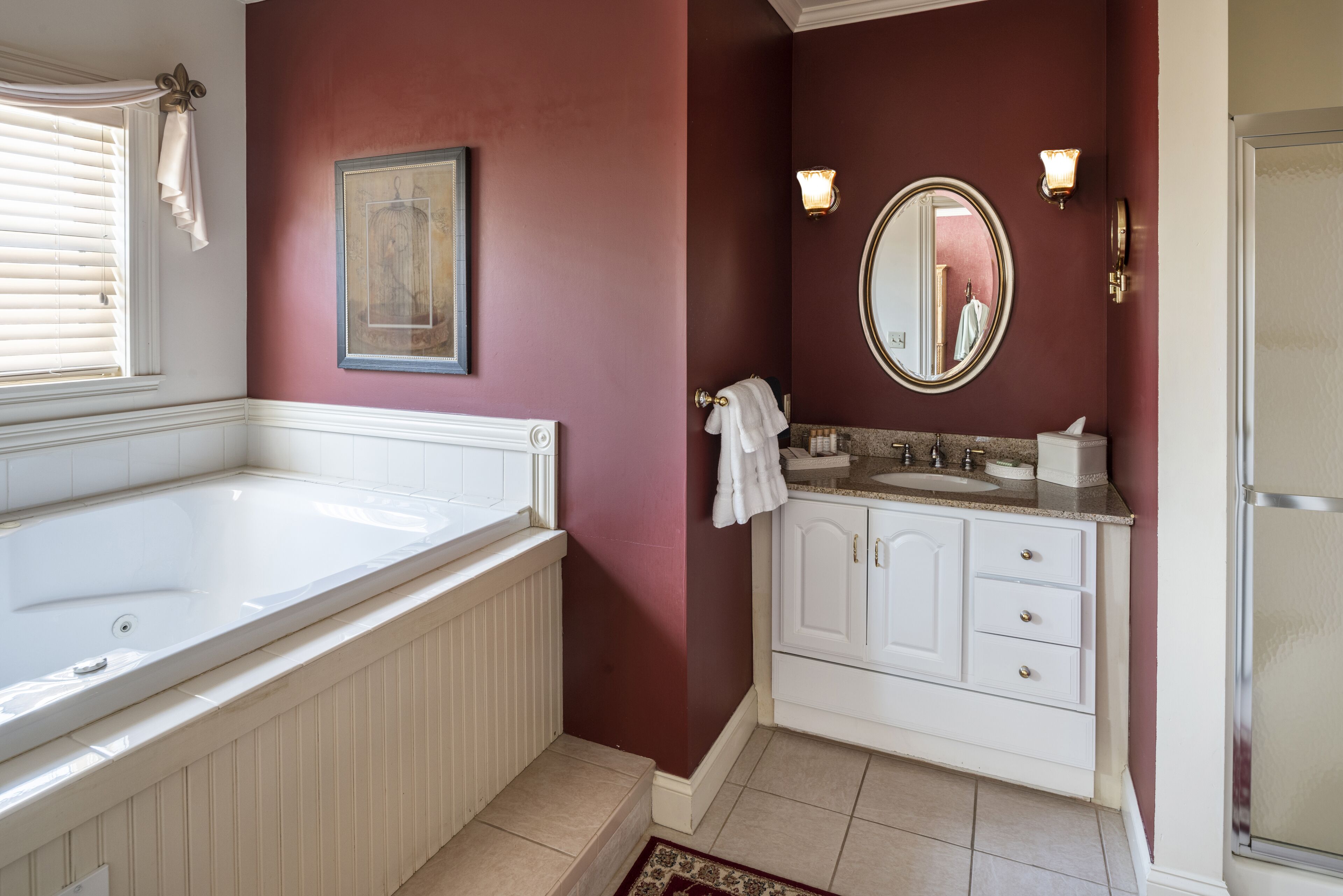 A bathroom with a large bathtub, a vanity with a mirror, and a shower area.
