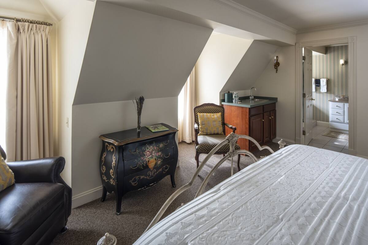 A bedroom with a bed, a dresser, a chair, and a desk.