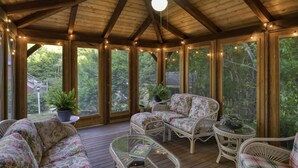 A covered porch with wooden beams, wicker furniture, and string lights. - The Inn at Thorn Hill & Spa (Jackson)