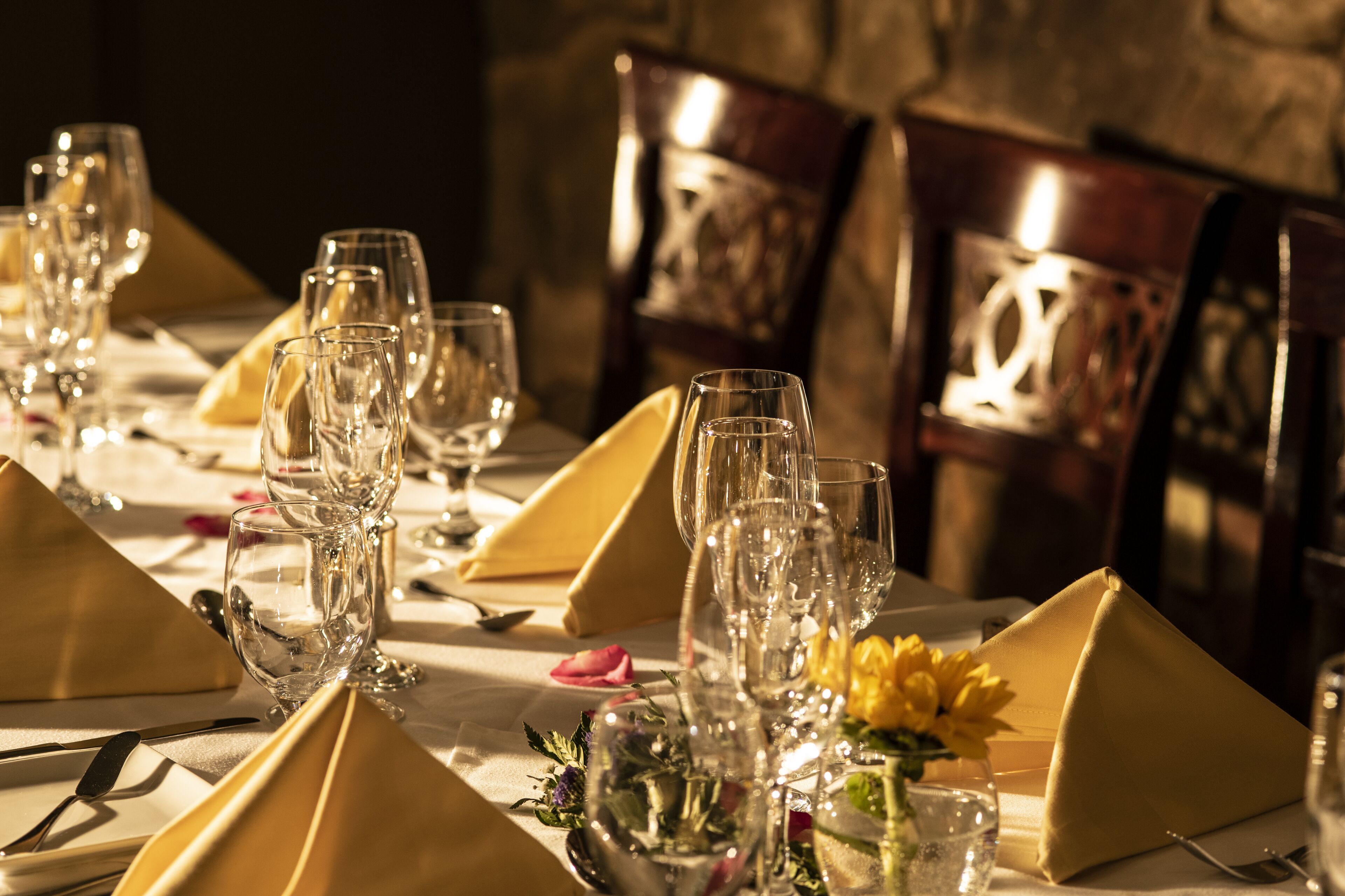 A table set for dining with clear glassware and yellow napkins.