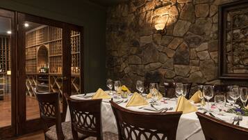 A dining area with a stone wall, wooden chairs, and a table set for a meal.