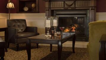 A cozy living room with a fireplace, a leather armchair, a coffee table with candles, and a yellow armchair.