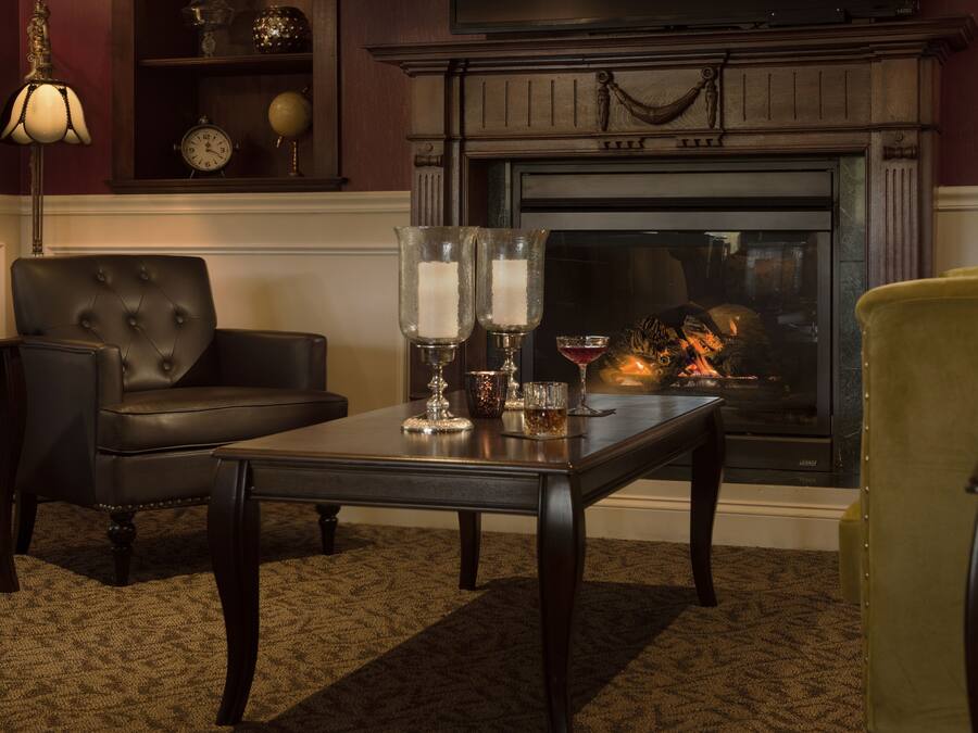 A cozy living room with a fireplace, a leather armchair, a coffee table with candles, and a yellow armchair.