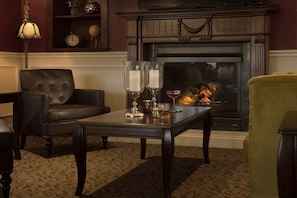 A cozy living room with a fireplace, a leather armchair, a coffee table with candles, and a yellow armchair.