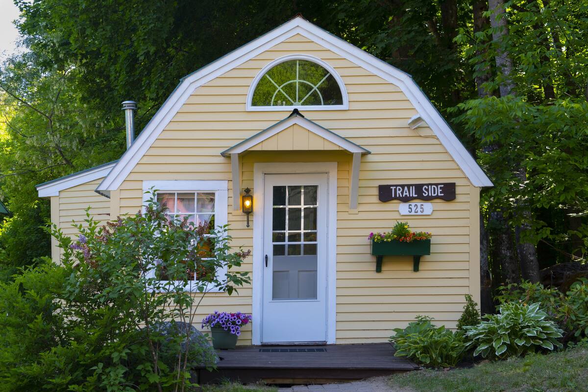 A small, single-story building with a white door and a window above it. There is a sign on the building that reads "TRAIL SIDE 525".
