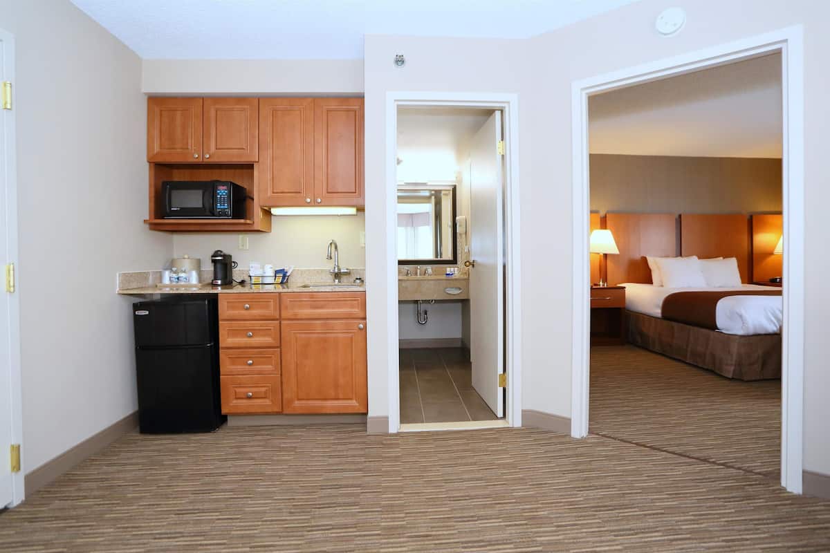 Ein Hotelzimmer mit einer Küchenzeile, einem Bett und einem Badezimmer.