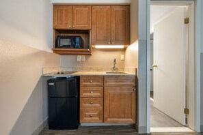 A compact kitchen with wooden cabinets, a built-in microwave, a refrigerator, and a sink. - Best Western La Plata Inn (La Plata)