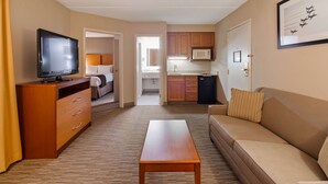 A hotel room with a TV, a sofa, a wooden table, a bed, and a kitchenette. - Best Western La Plata Inn (La Plata)