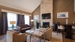 A modern living room with a stone fireplace, comfortable seating, and a dining area. - Best Western La Plata Inn (La Plata)