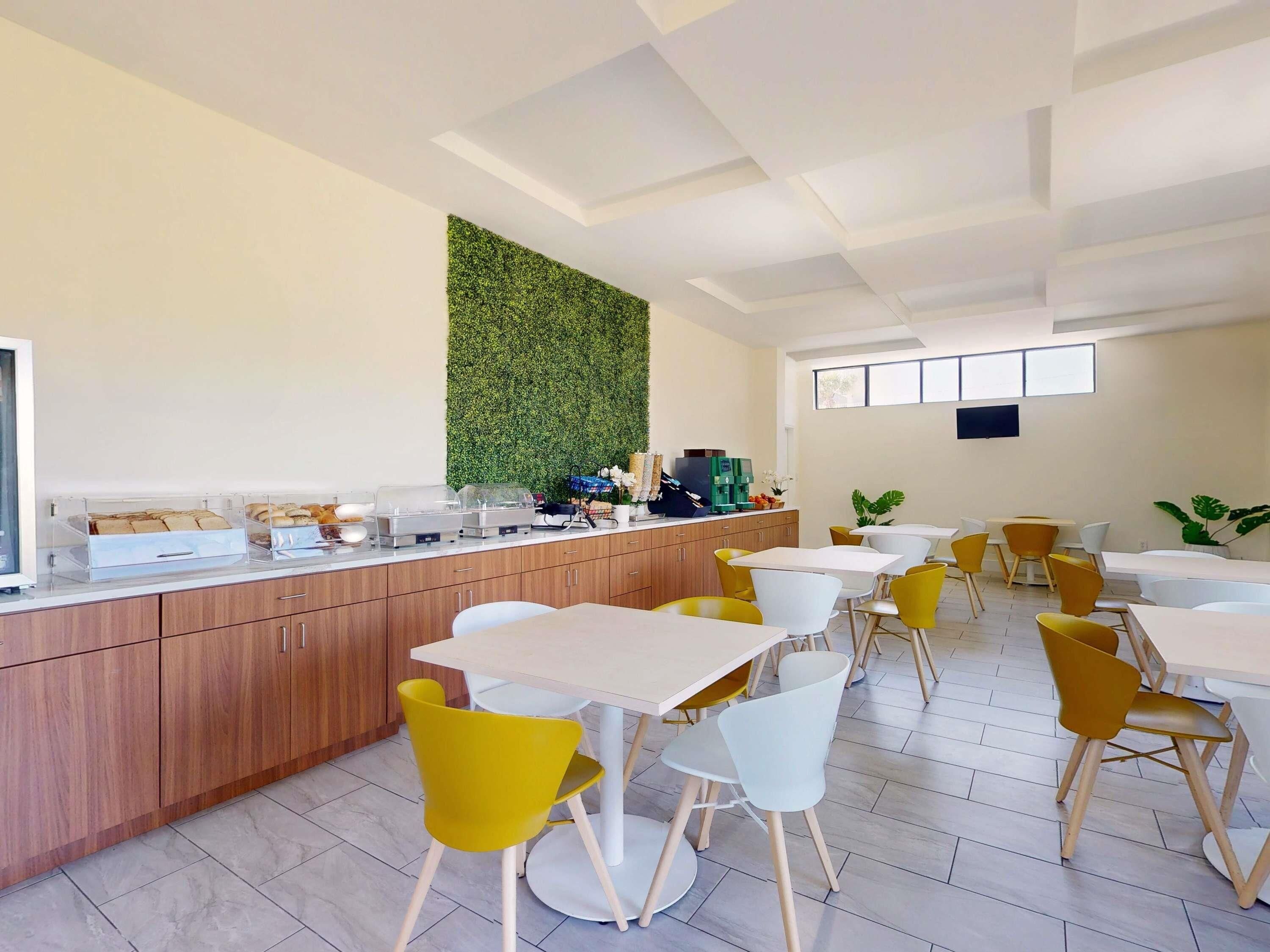 Un área de comedor moderna con mostrador, asientos y una pared verde.