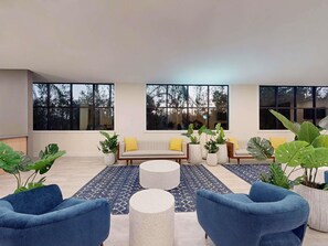A modern living room with a sofa set, blue armchairs, and round coffee tables. - Park Royal Orlando managed by Accor (Kissimmee)