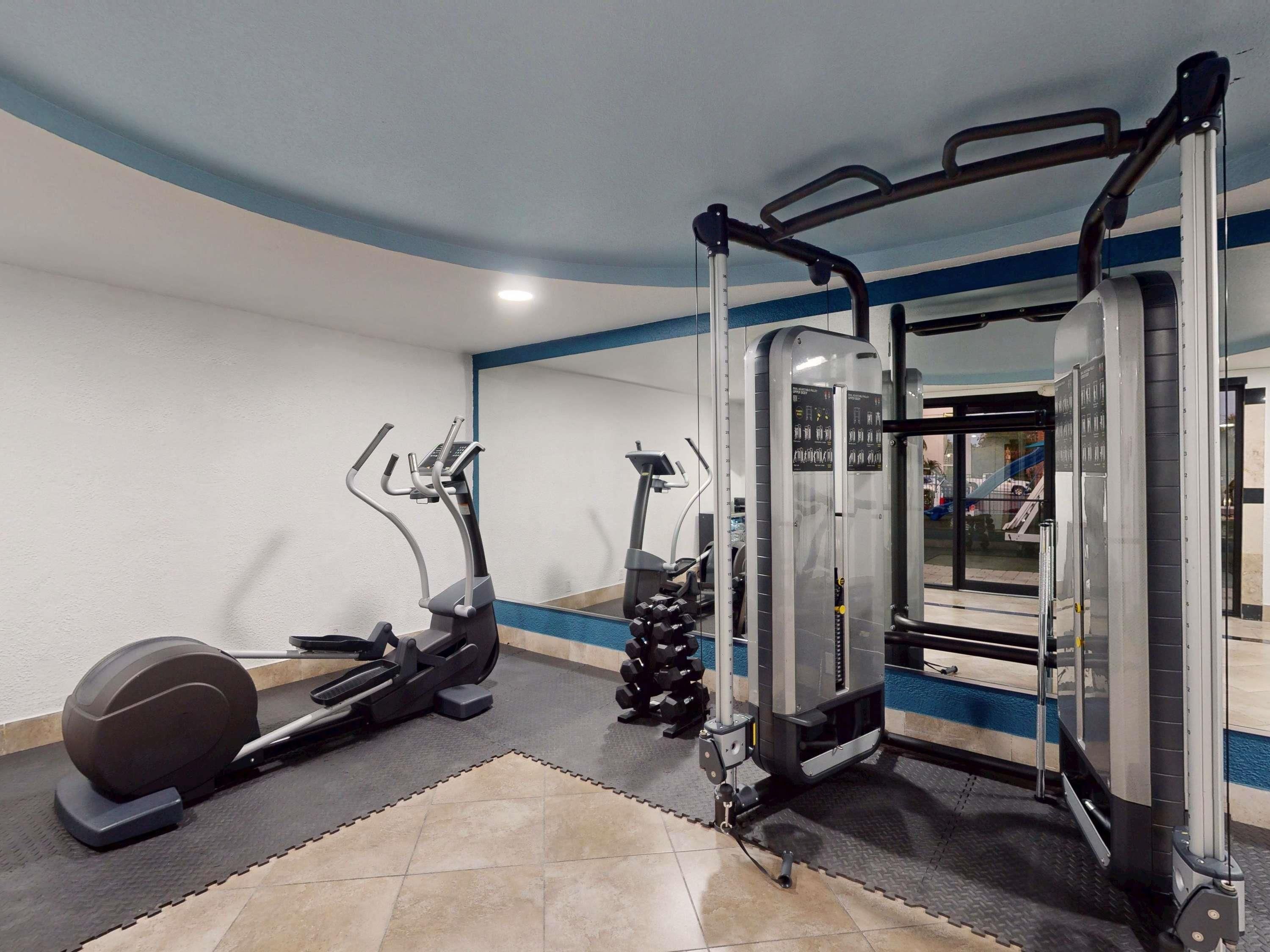 A gym with exercise equipment including treadmills, a weight machine, and a mirror.