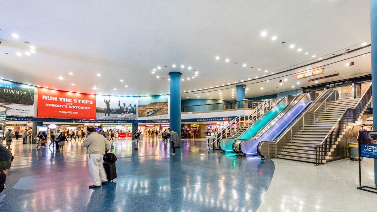 A spacious indoor area with escalators, a central column, and a large advertisement.