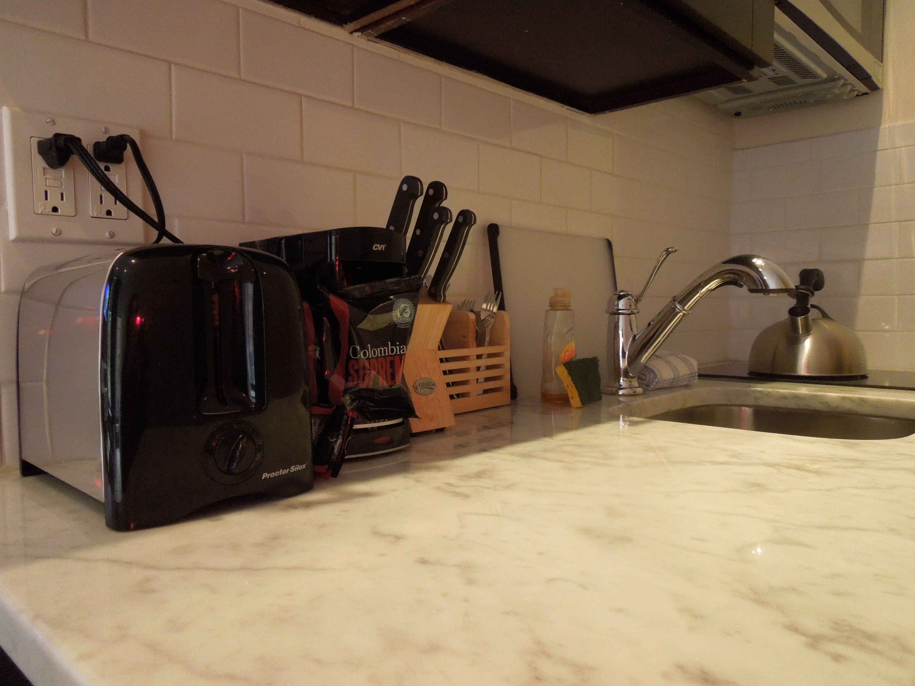 Una encimera de cocina con un tostador, una cafetera, un bloque de cuchillos y un hervidor.