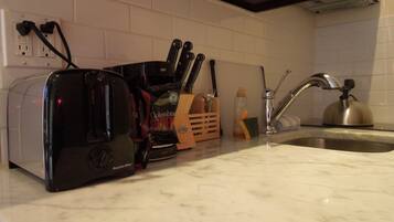 A kitchen counter with a toaster, a coffee maker, a knife block, and a kettle.