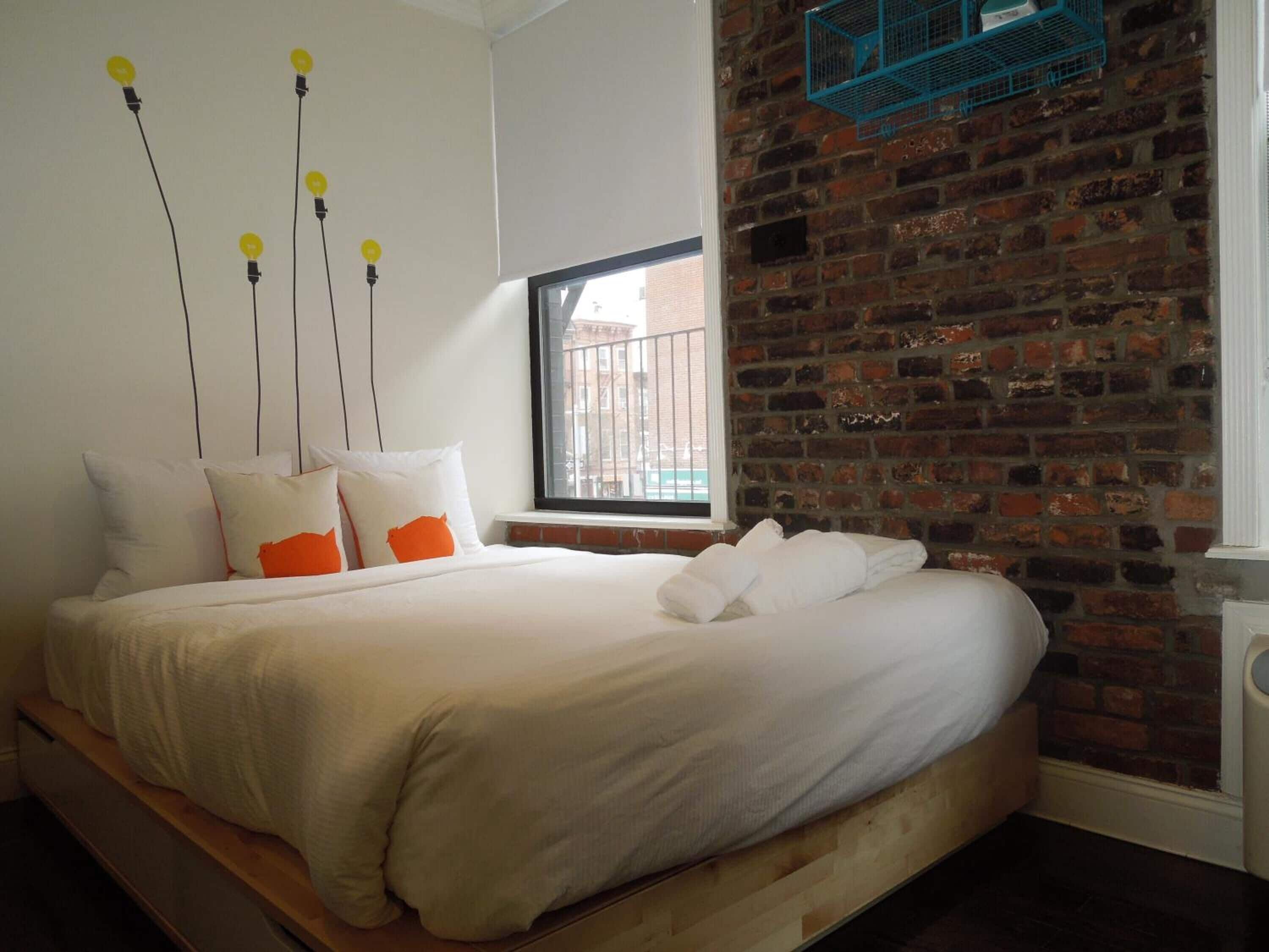 Ein Schlafzimmer mit Backsteinwand, hölzernem Bettgestell und einem Fenster mit Blick auf Gebäude.