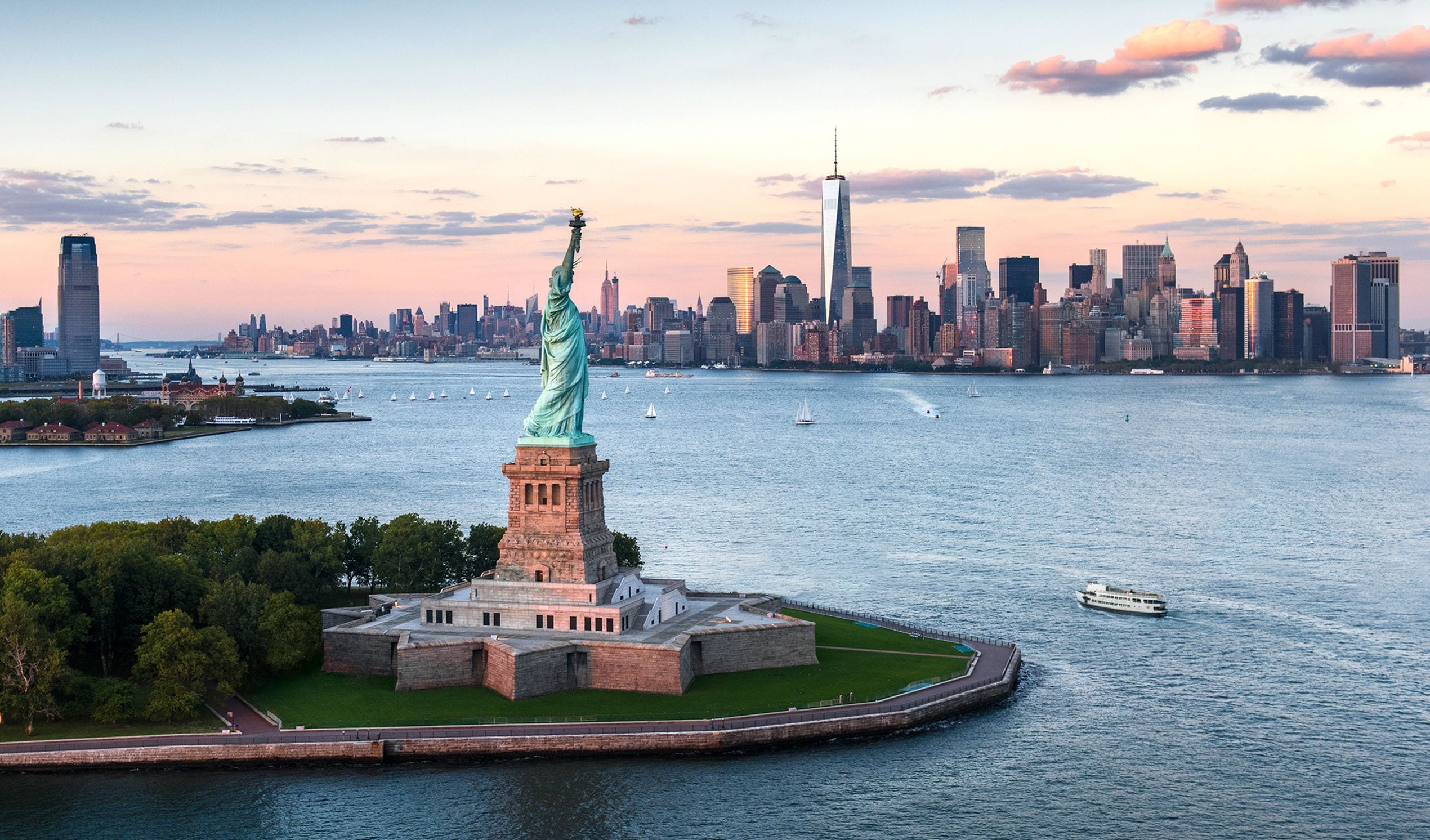 The Statue of Liberty in New York City, surrounded by water with a city skyline in the background.