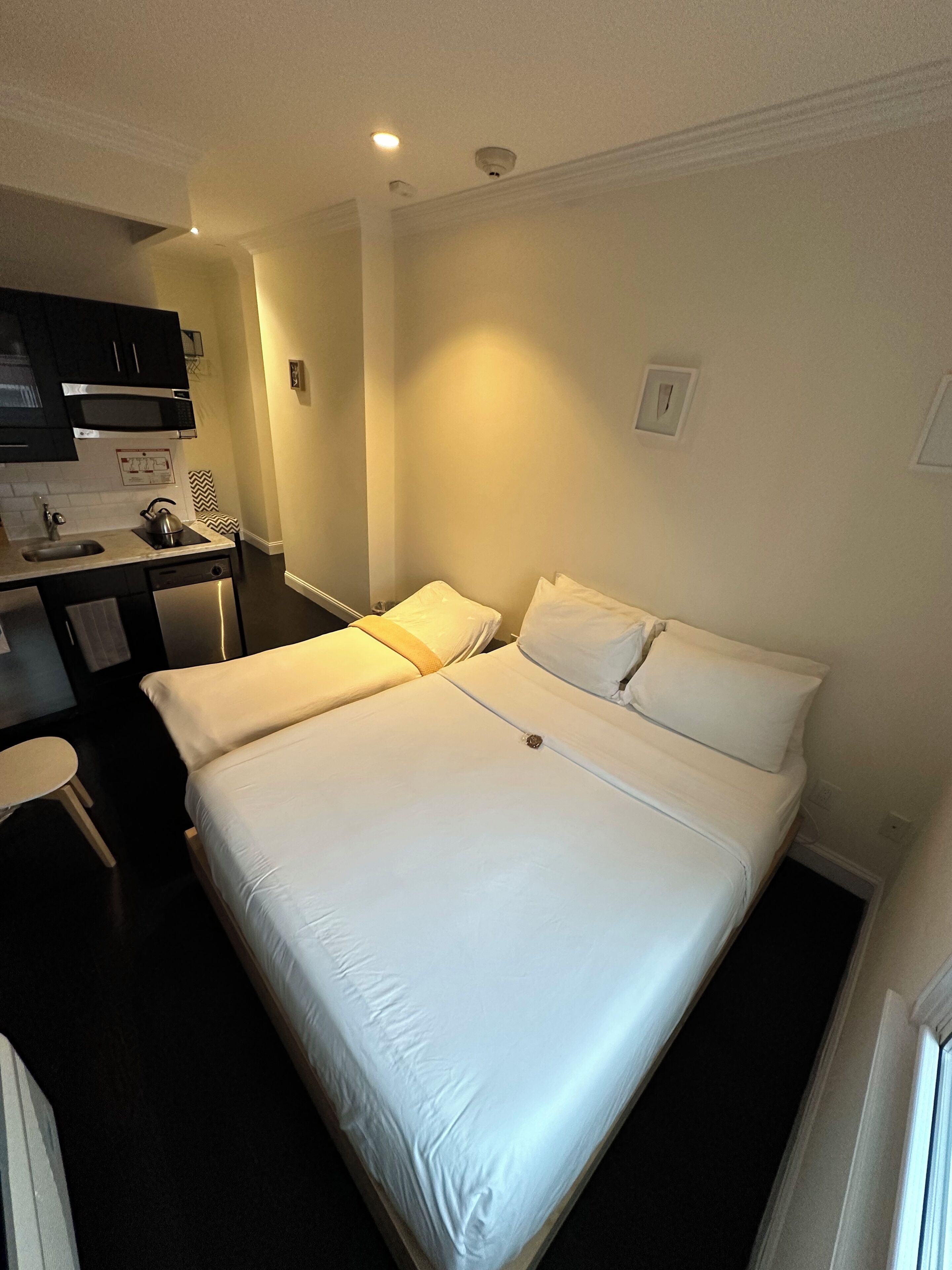 Une chambre d’hôtel comprenant un lit, un bureau avec un micro-ondes, une chaise et une petite table.