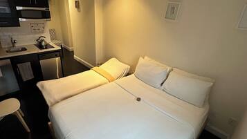 Une chambre d’hôtel comprenant un lit, un bureau avec un micro-ondes, une chaise et une petite table.