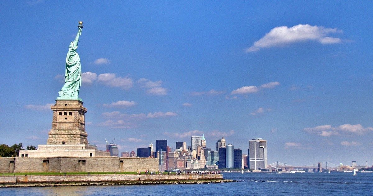 The Statue of Liberty in New York City with the Manhattan skyline in the background.