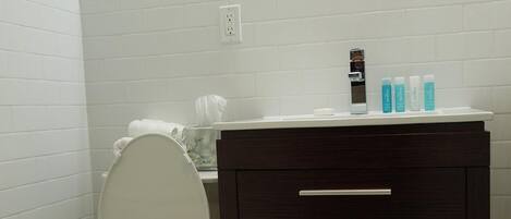 A bathroom with a white toilet, dark wooden vanity, and a mirror above the sink.