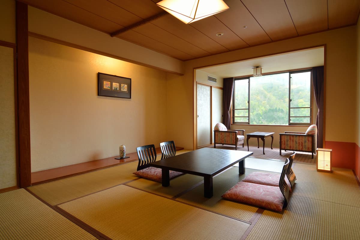 Ein traditioneller japanischer Raum mit Tatami-Böden, einem niedrigen Tisch und Sitzgelegenheiten.