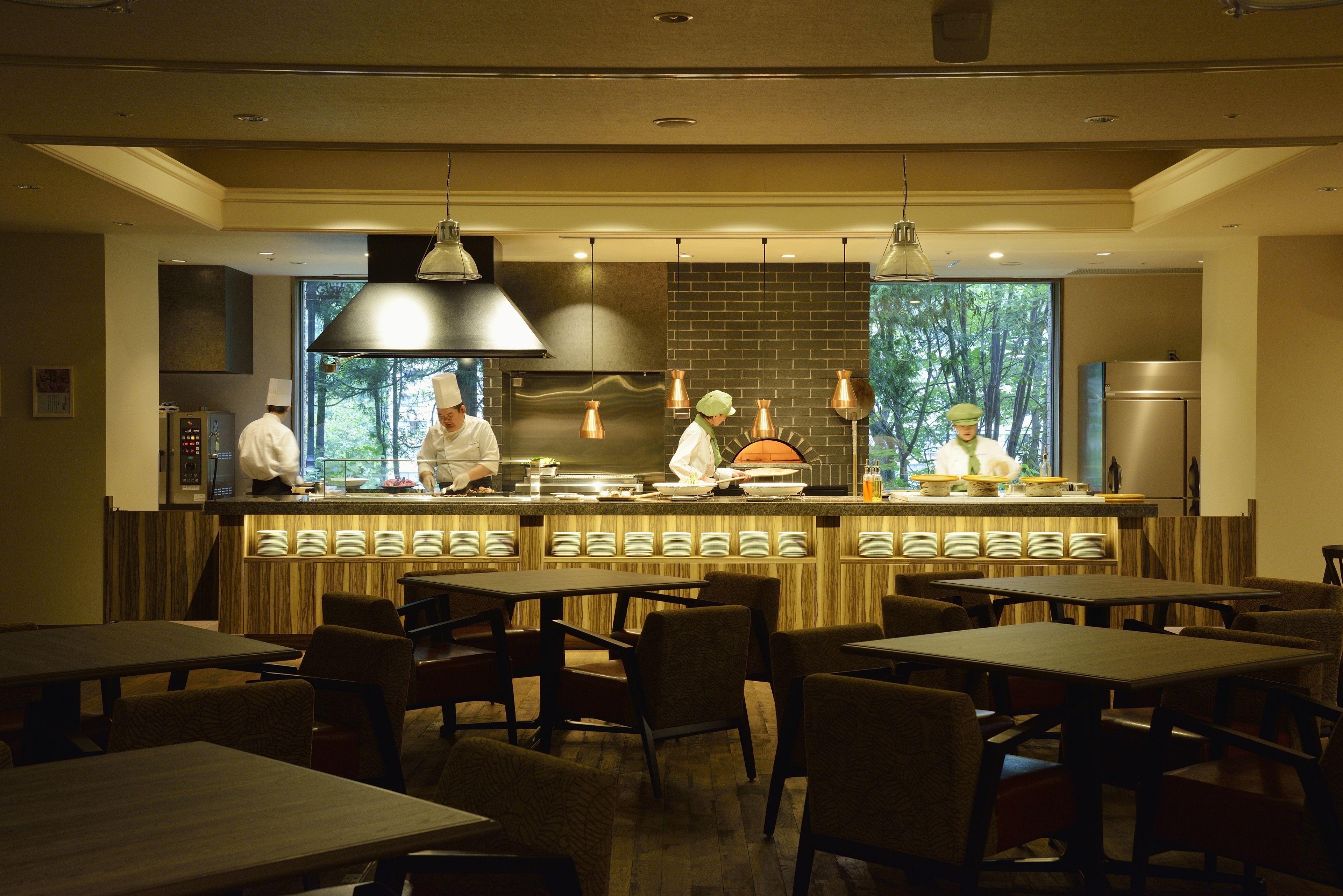 A modern restaurant interior with a bar area, multiple seating arrangements, and a view of the outdoors through large windows.