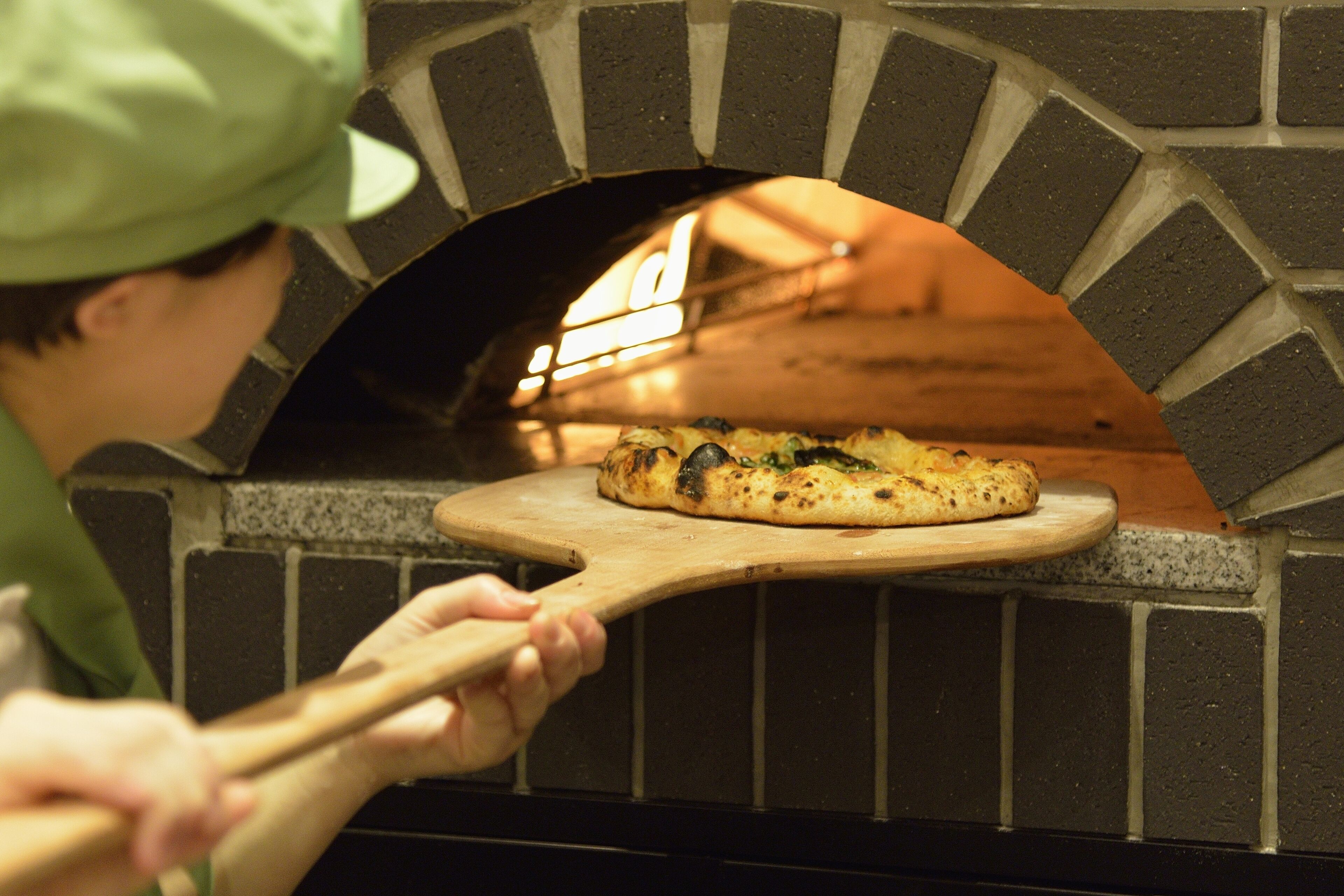Eine Pizza wird aus einem Ziegelofen genommen.