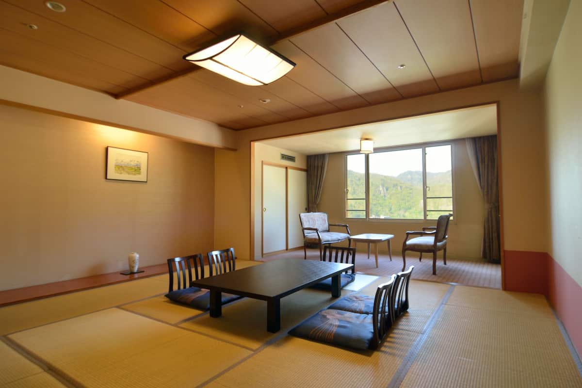 Ein traditioneller japanischer Raum mit Tatami-Böden, einem niedrigen Tisch und Sitzgelegenheiten.