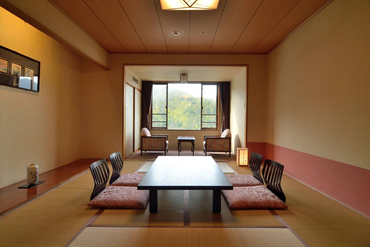 Ein traditioneller japanischer Raum mit Tatami-Böden, einem niedrigen Tisch und vier Stühlen.