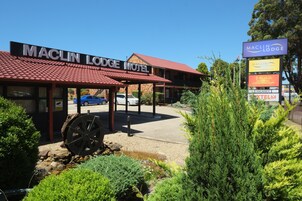 El motel Maclin Lodge, con techo de tejas rojas, zona de estacionamiento cubierta y un letrero que anuncia un restaurante chino y una habitación disponible.