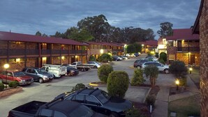 A hotel with multiple rooms, a parking lot, and a landscaped area with trees. - Maclin Lodge Motel (Campbelltown)