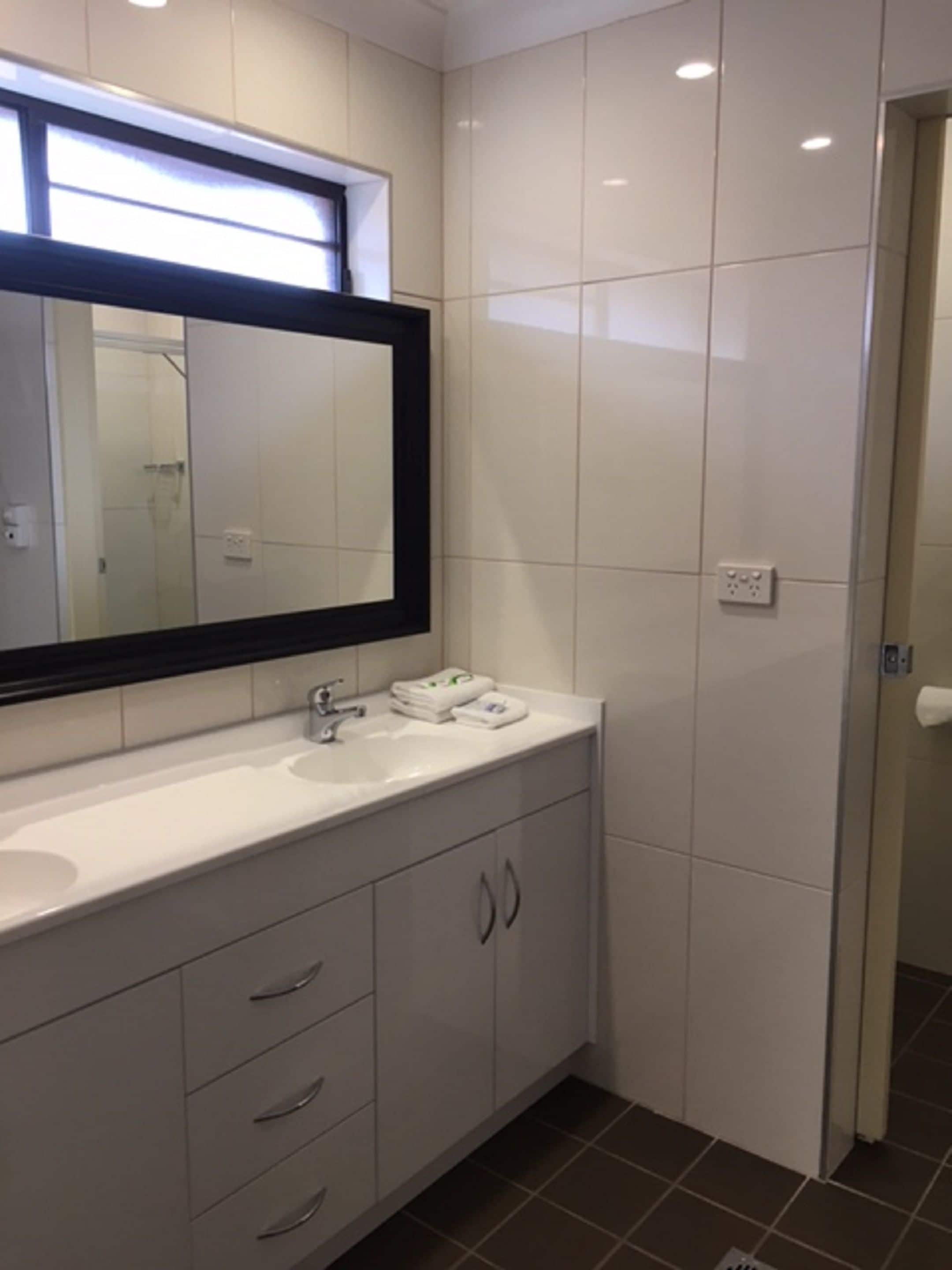 Un bagno moderno con un grande specchio, un lavandino bianco e pensili.
