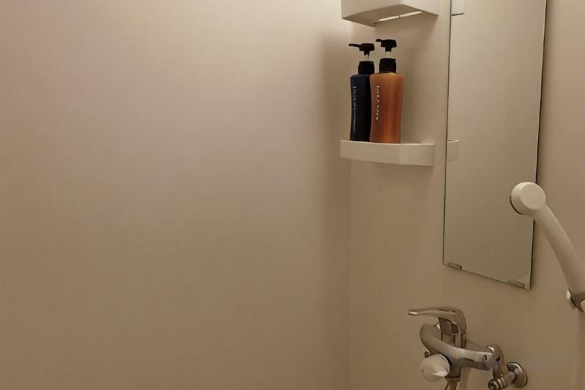 Une salle de bain équipée d’un miroir, d’un porte-serviettes et d’une étagère où sont rangés les articles de toilette.