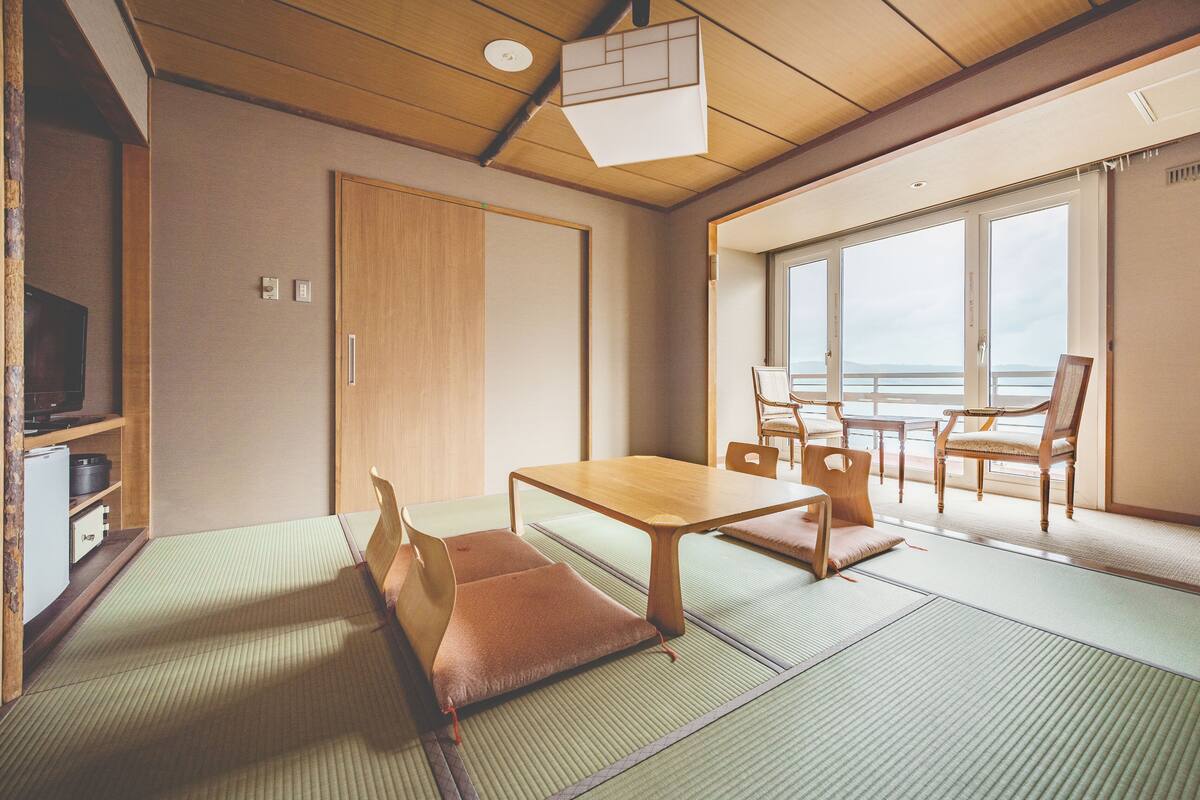 Une pièce de style japonais traditionnel, avec un sol recouvert de tatamis, une petite table en bois et des chaises.