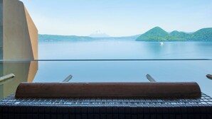 Uitzicht vanaf een balkon met een heldere lucht, kalm water en verre bergen.