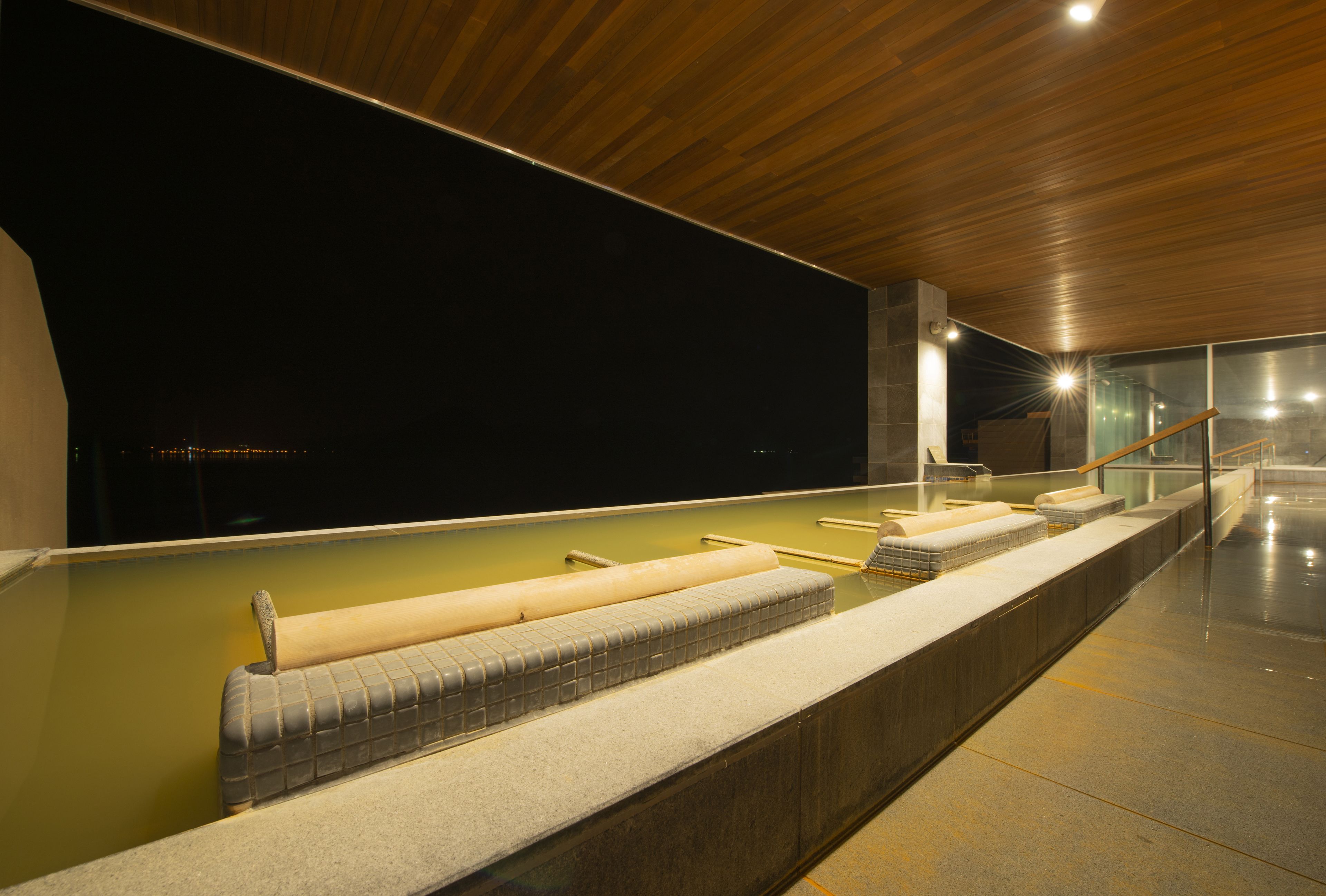 A spa area with a long bench, a small pool, and a wooden ceiling.