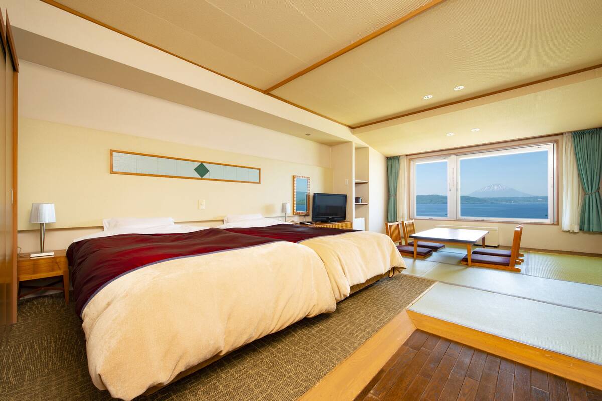 Une chambre d’hôtel avec un grand lit, une télévision, un bureau et une vue sur une montagne par la fenêtre.